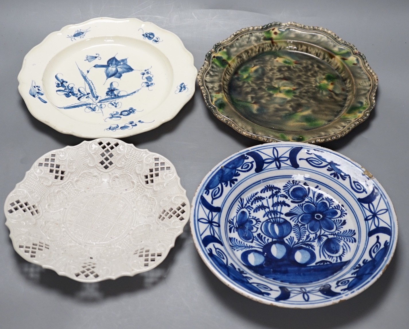 A Staffordshire salt glaze plate with pierced border, a Staffordhire tortoiseshell painted plate, a creamware underglaze blue plate and a Dutch delft plate, salt glazed plate 21 cms diameter